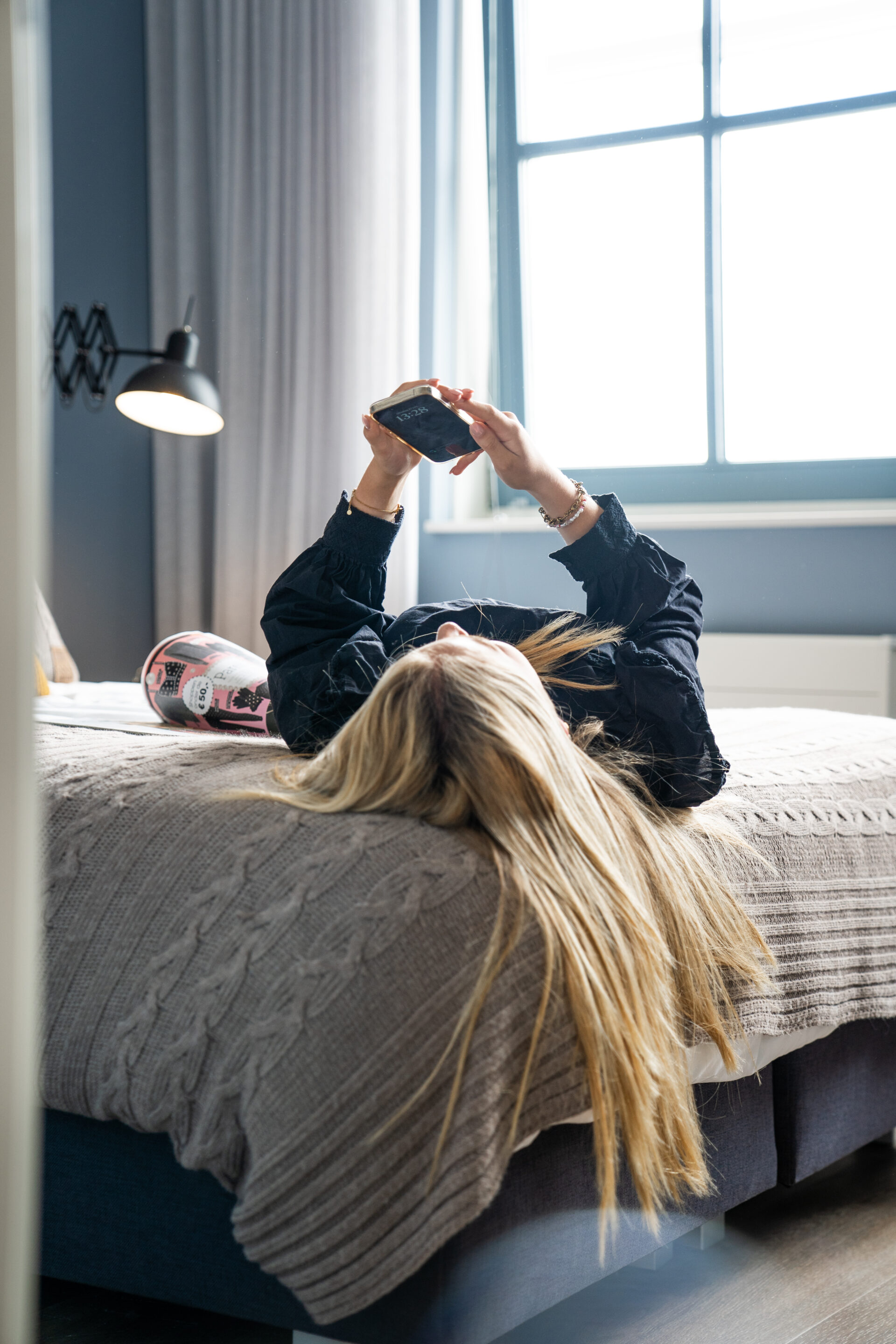 Foto van jonge vrouw liggend op bed met haar telefoon